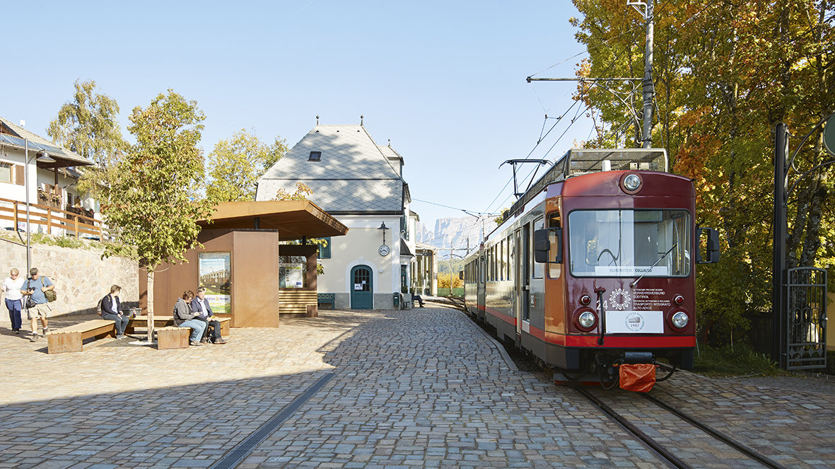 Persone in attesa alla fermata di Soprabolzano. Trenino del Renon in partenza.