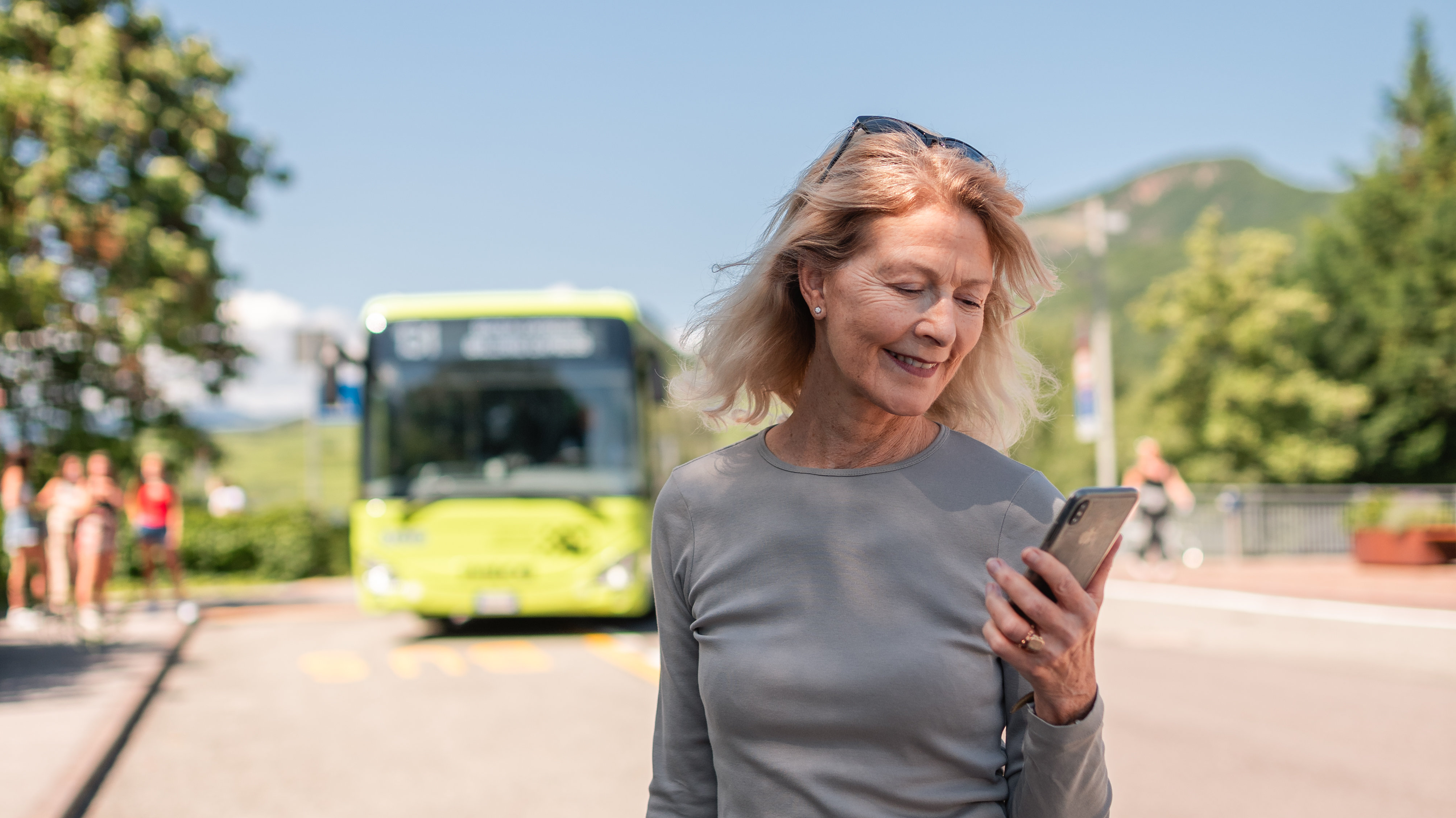 Woman with mobile next to a bus