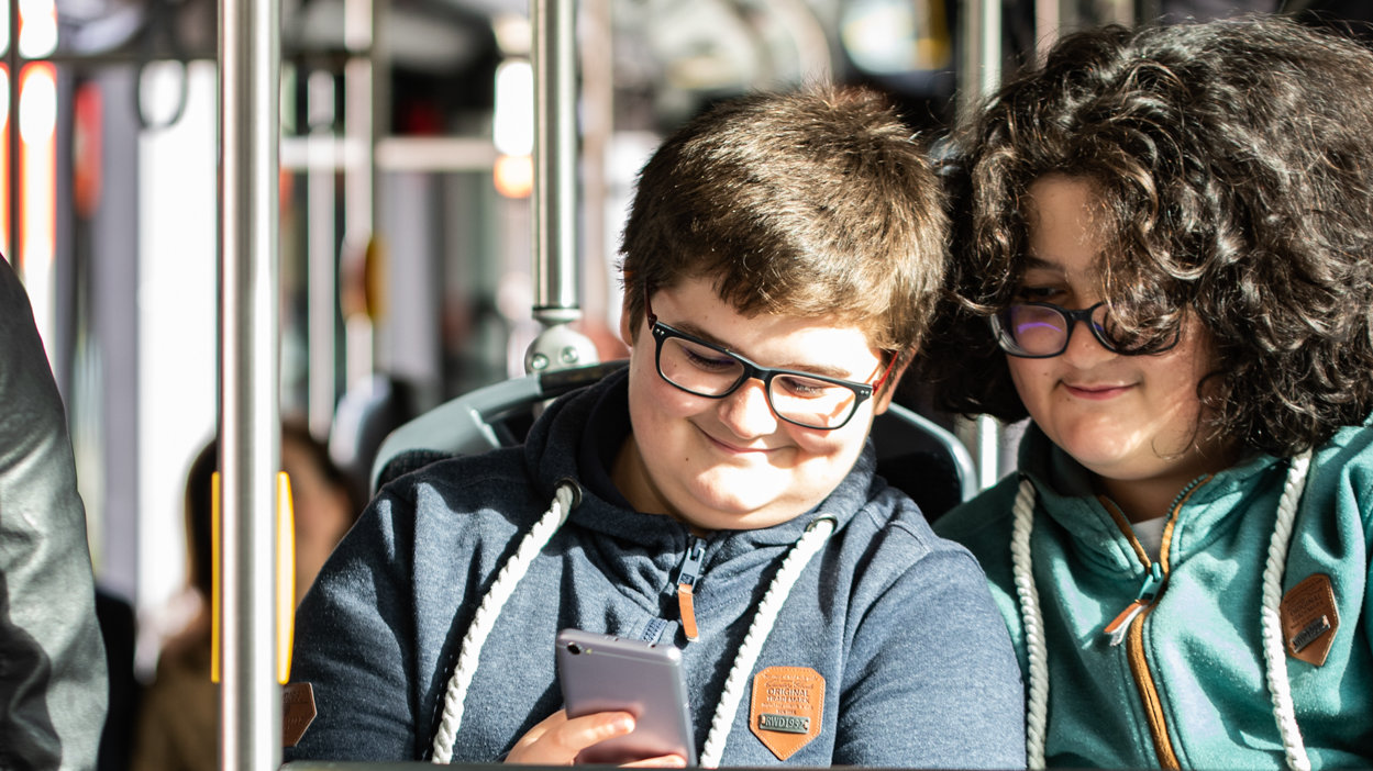 Two young people are checking the phone on the bus.